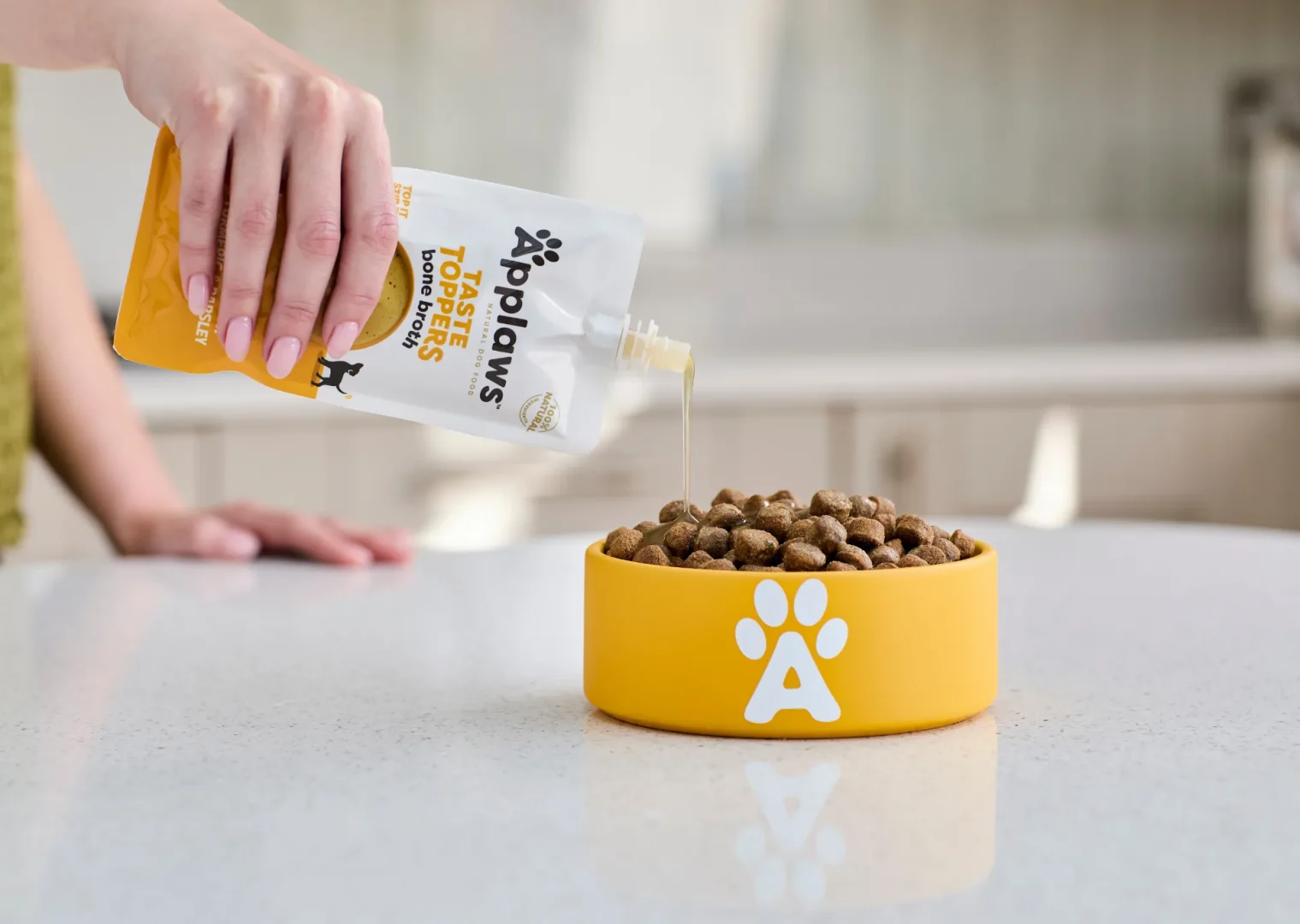 Pouring Applaws Chicken Bone Broth onto a bowl or Applaws Dry Dog Food